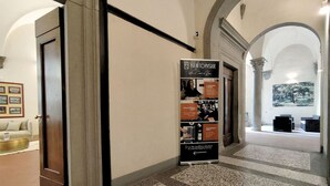 A hallway with a poster advertising a community event. There are columns and a framed picture on the wall. - Tiepolo romantic penthouse in the Oltrarno (Firenze)