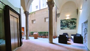 A spacious courtyard with a large planter, a mural, and a seating area. - Tiepolo romantic penthouse in the Oltrarno (Firenze)