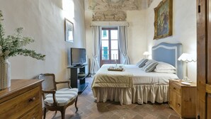 Een slaapkamer met een bed, een televisie, een bureau en een stoel.