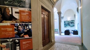 An entrance with a common doorway, a hallway leading to a lounge area, and a poster advertising a community lounge and shared fitness center.