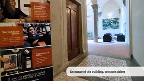 An entrance with a common doorway, a hallway leading to a lounge area, and a poster advertising a community lounge and shared fitness center. - Tiziano big penthouse in the Oltrarno (Firenze)