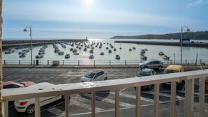 Un port où de nombreux bateaux sont amarrés, un ciel dégagé et une route bordée de voitures garées.