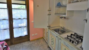 A kitchen with a gas stove, sink, and open cabinets.