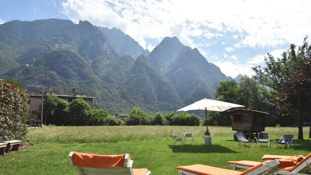 A grassy area with lounge chairs and an umbrella, overlooking a mountainous landscape.