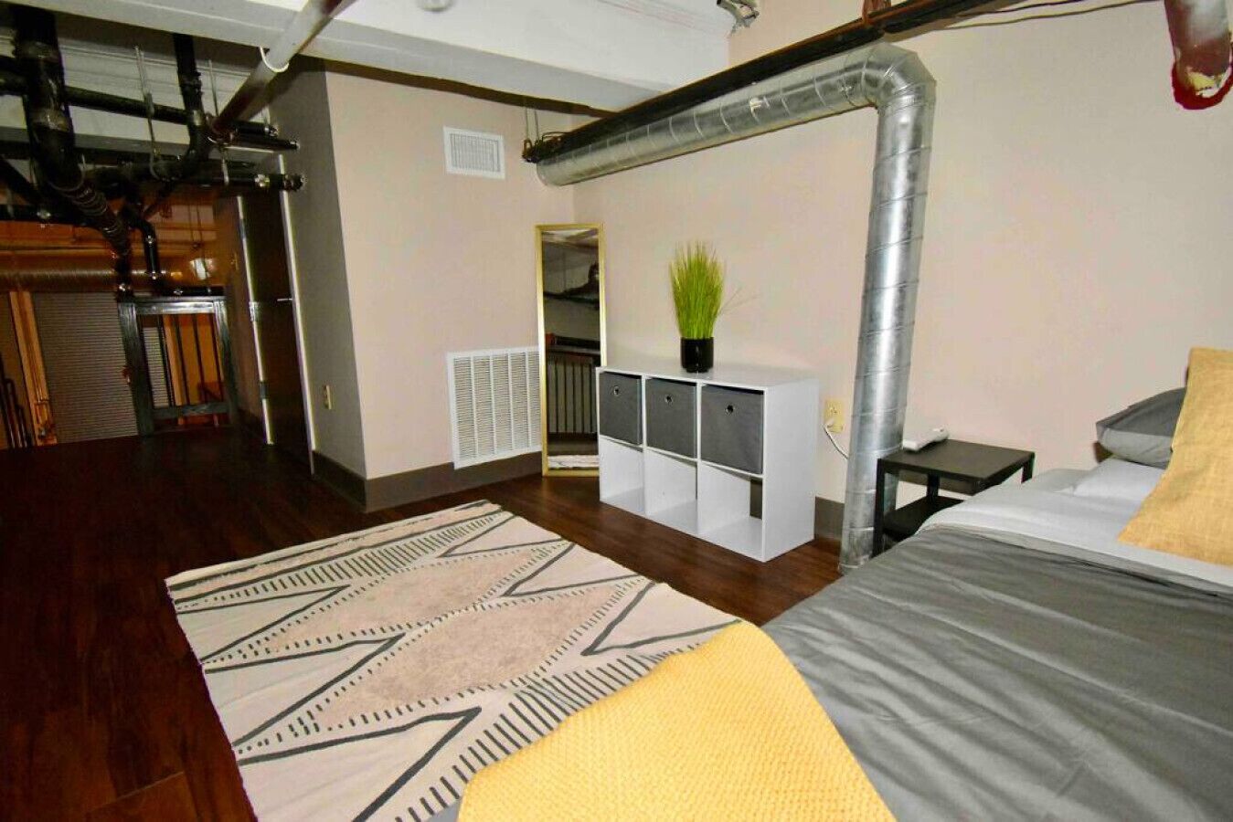 Ein modernes Schlafzimmer mit einem großen Bett, einem Schreibtisch, einem Heizkörper und einer Pflanze.