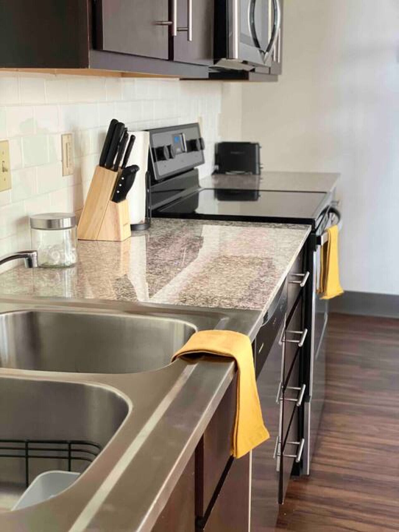 A modern kitchen with stainless steel appliances, a granite countertop, and wooden cabinets.