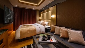 Een hotelkamer met twee bedden, een televisie, een nachtkastje met dienblad en een bank.