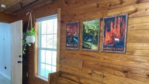 A wooden interior with a bench, a hanging plant, and three posters of Mammoth Cave.