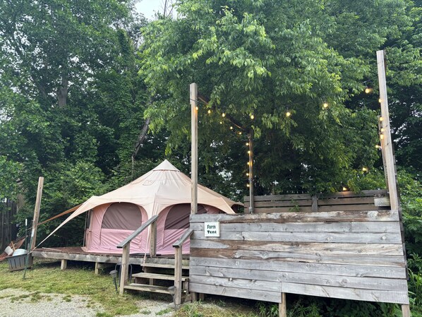 Una tienda de campaña con una plataforma de madera y un letrero que dice 'Farm Tent'.