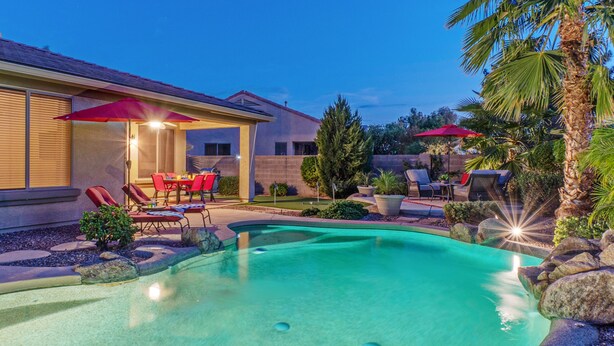 A swimming pool with a sunken seating area, surrounded by rocks and palm trees. - Resort Amenities: Pvt Htd POOL, Putt Green, Patio & Gas Grill & Fire Tbl, TVs All BRs, (Gilbert)