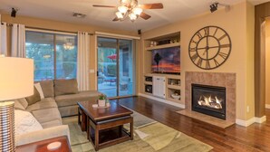 A living room with a sofa, coffee table, fireplace, and a large clock on the wall. - Resort Amenities: Pvt Htd POOL, Putt Green, Patio & Gas Grill & Fire Tbl, TVs All BRs, (Gilbert)