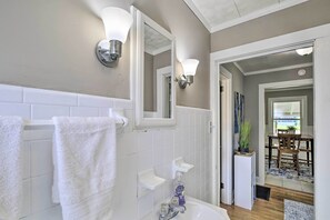 Bathroom features a bathtub, sink, and mirror with wall-mounted lighting.