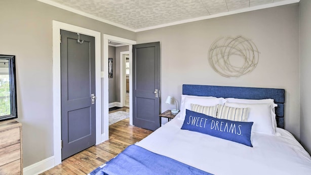A bedroom with a bed, a nightstand, a wall decoration, and two doors leading to other rooms. - Cozy Cottage Near Dtwn Dining, Walk to Casino (Bristol)