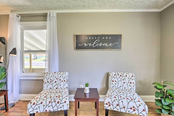Relax in this inviting space with two comfortable chairs, a small table, and a potted plant.