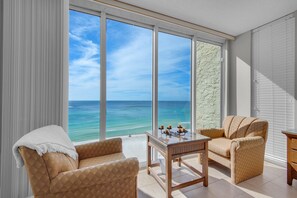 Enjoy ocean views from the large window in this room, featuring two armchairs and a small table.