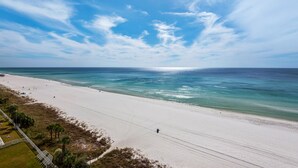 Una playa con cielo despejado, orilla arenosa y algunas personas.