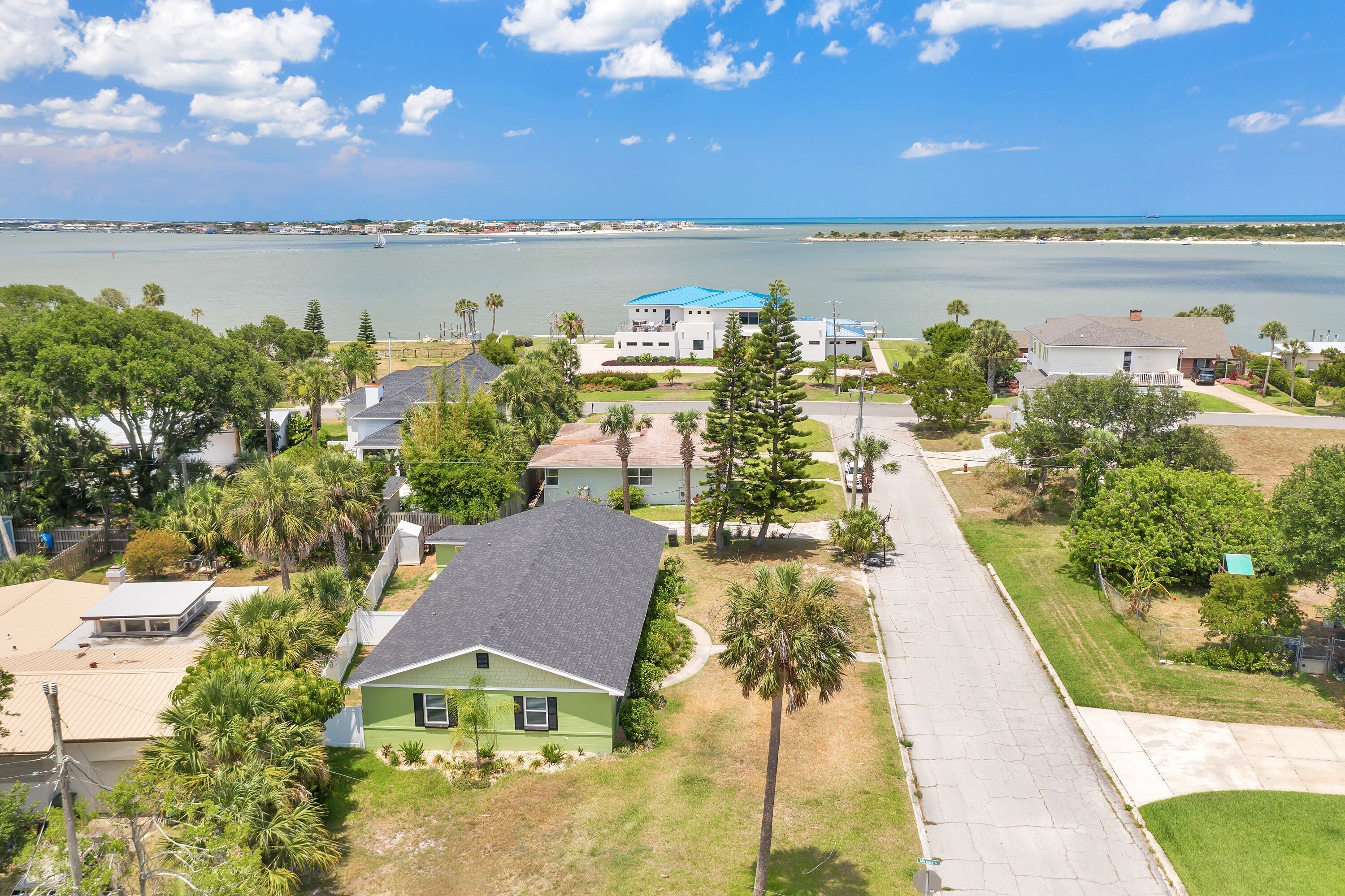 A residential area with houses, a street, and a body of water in the background.