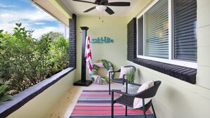 A balcony with a ceiling fan, a striped rug, two wicker chairs, a potted plant, and a sign that reads "Saltlite." - Here Comes The Sun! King Bed - One block to the water Unit #4 (St. Augustine)