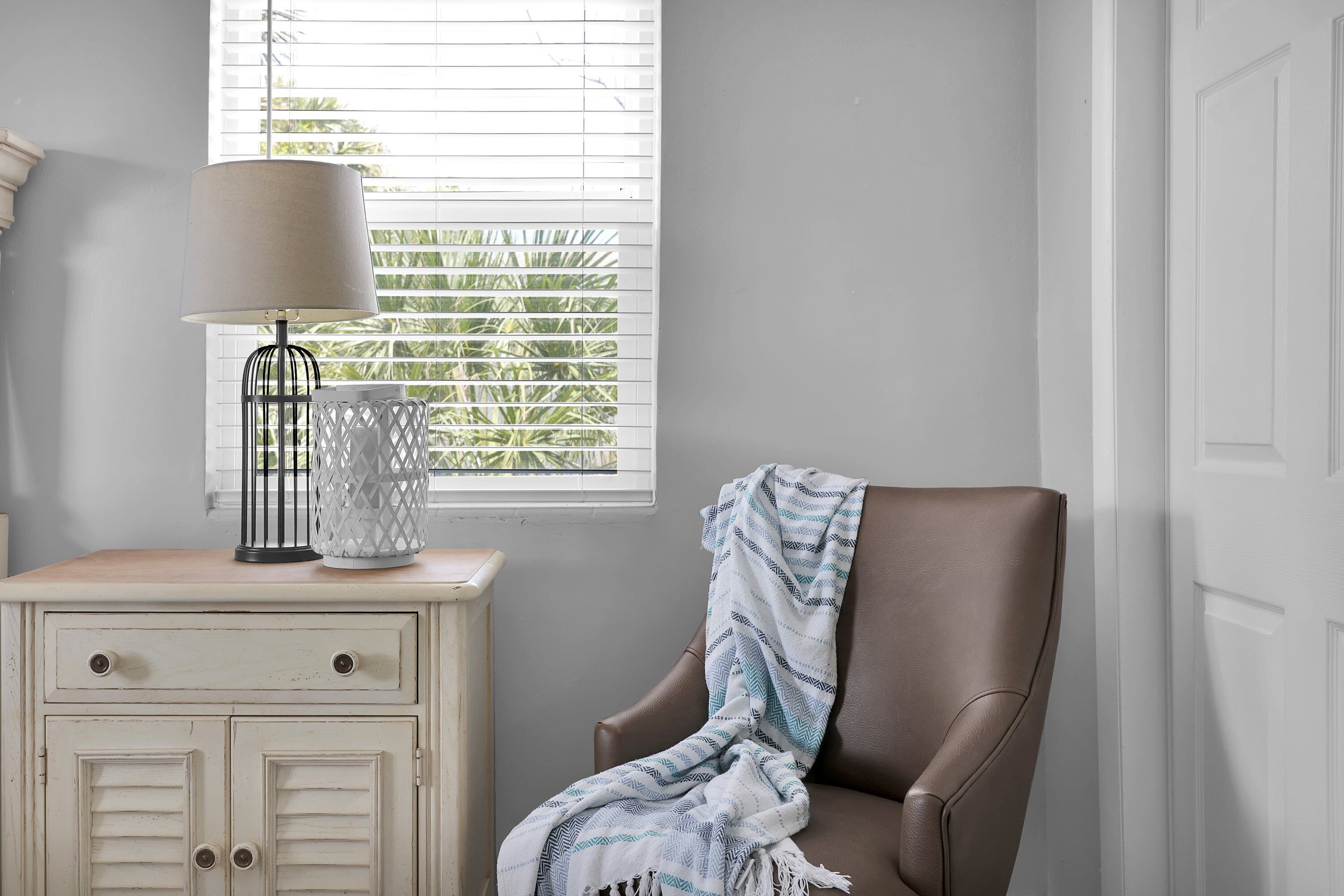 A room with a window, a lamp, a chair, and a cabinet.