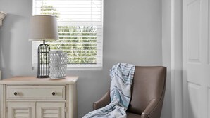 A room with a window, a lamp, a chair, and a cabinet. - Here Comes The Sun! King Bed - One block to the water Unit #4 (St. Augustine)