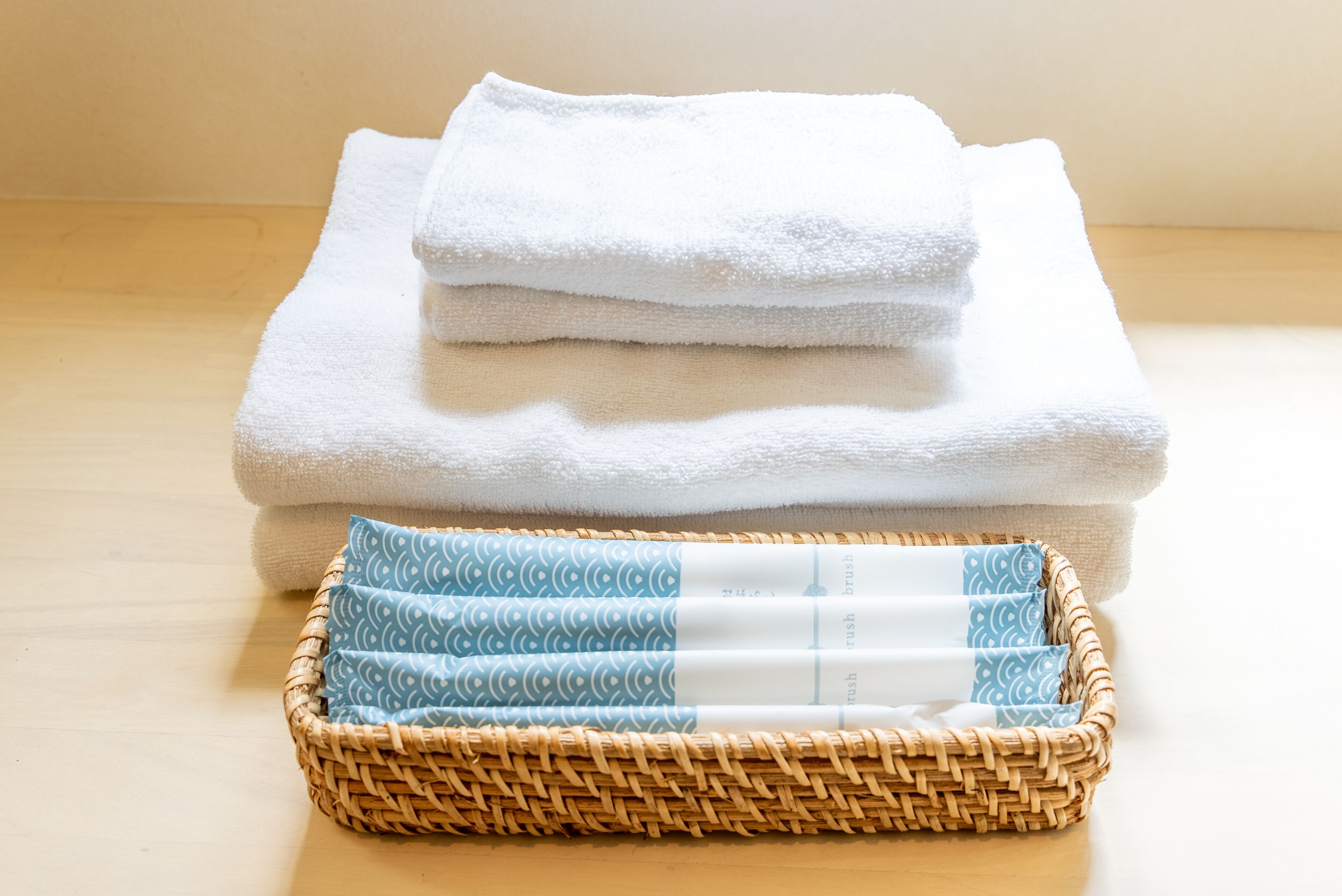 A stack of white towels and a basket with patterned towels.