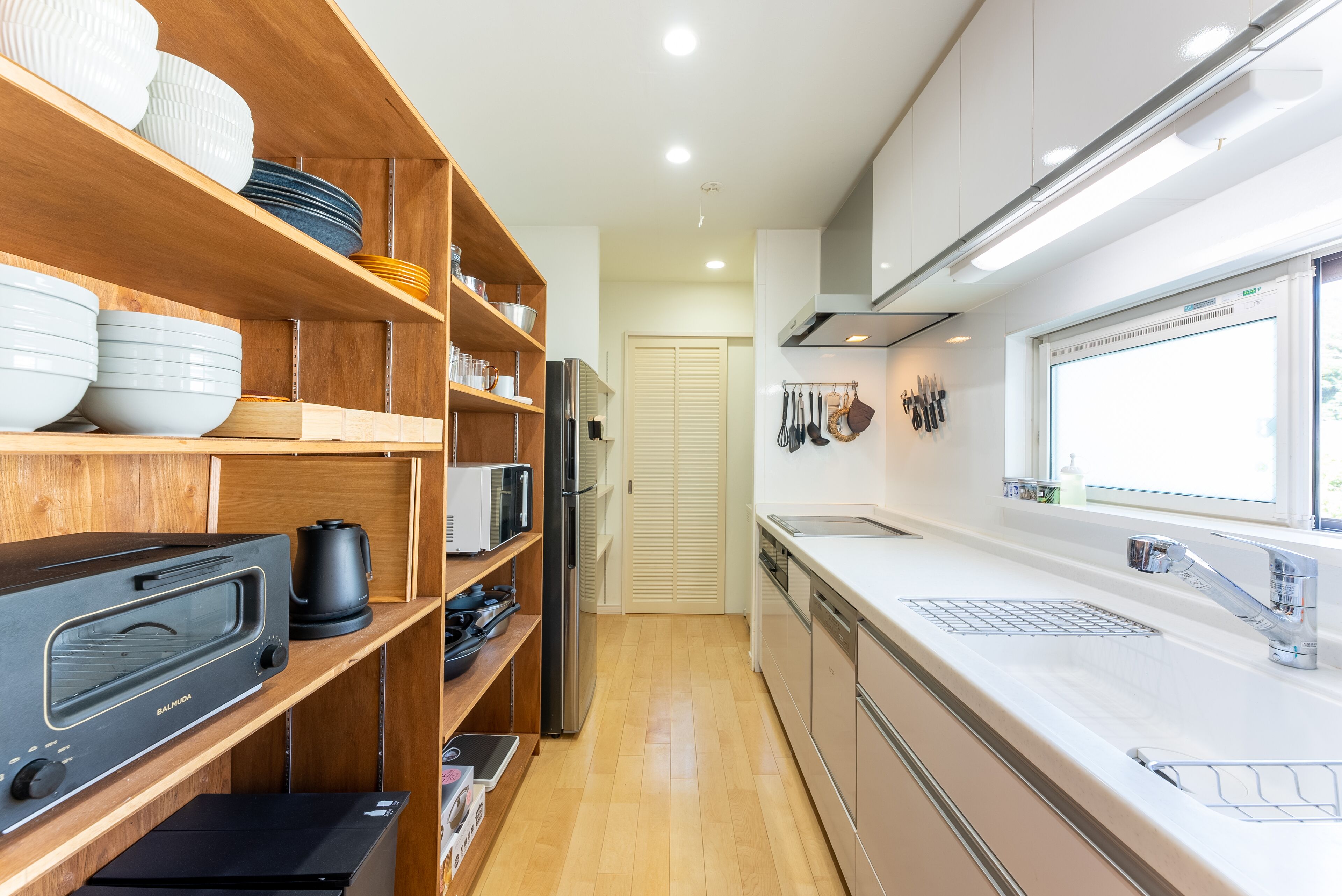 Una cucina moderna con scaffali in legno, forno incassato e lavello in acciaio inossidabile.
