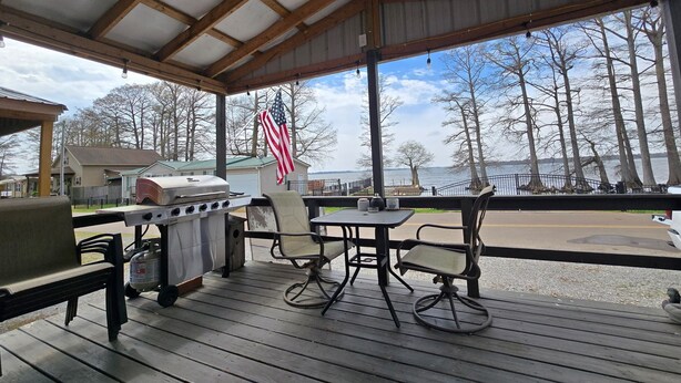 A covered outdoor area with a grill, chairs, and a table. - Come and relax at the Refuge at beautiful Reelfoot Lake! (Hornbeak)