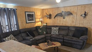 A living room with a sectional sofa, a coffee table, a lamp, and wall-mounted bird decorations. - Come and relax at the Refuge at beautiful Reelfoot Lake! (Hornbeak)