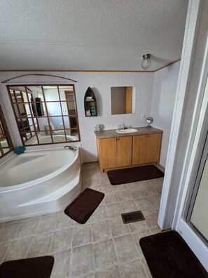 Une salle de bain équipée d’une baignoire, d’un lavabo, d’un meuble-lavabo, d’un miroir et d’une étagère où sont rangés les articles de toilette.
