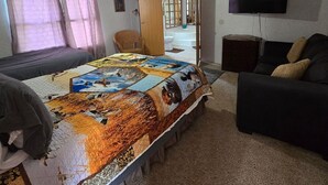 A hotel room with a bed, a sofa, a TV, and a bathroom visible through an open door. - Come and relax at the Refuge at beautiful Reelfoot Lake! (Hornbeak)