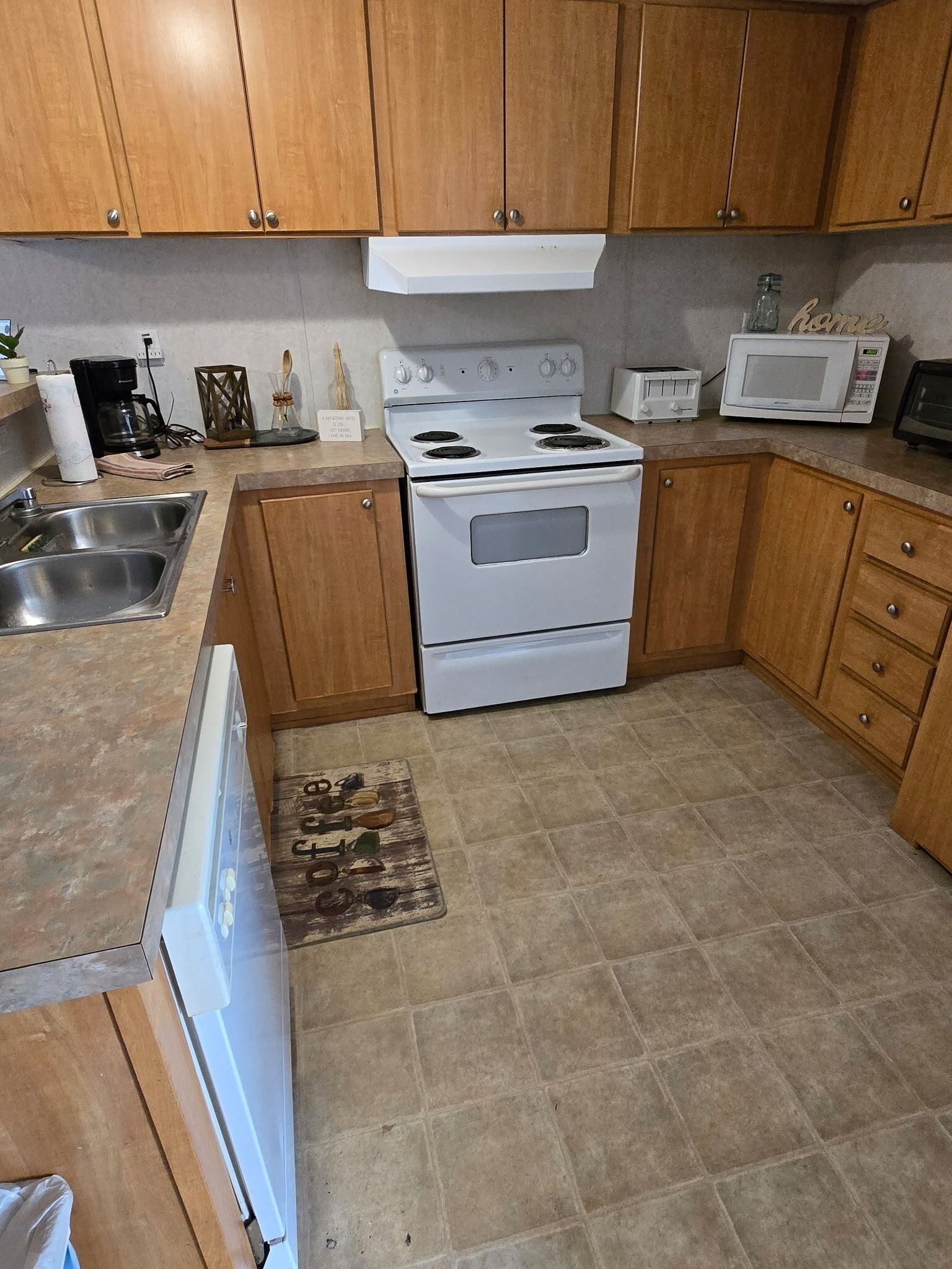 A kitchen with wooden cabinets, a white stove, a microwave, and a sink.