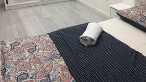 Une chambre avec un grand miroir, un lit avec une literie à motifs, une table de chevet et une armoire.