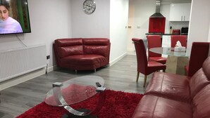 Un salon moderne avec un canapé en cuir rouge, une table basse en verre et un tapis rouge à longues mèches.