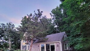 A two-story house with a brick exterior, large windows, and a covered patio area.