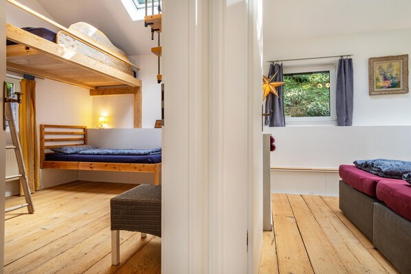 Una habitación con literas, un escritorio, una silla, una ventana con cortinas y una decoración con motivos de estrellas.