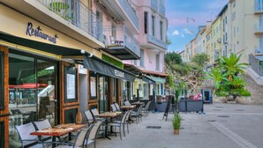 A restaurant with outdoor seating, a signboard, and a staircase leading to a building with balconies. - Au Vieux Port Cannes City Center, Cannes, France (Cannes)