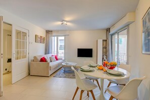 A modern living room with a sofa, dining table, and chairs.