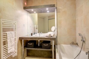 Ein Badezimmer mit Waschbecken, Spiegel, Handtuchhalter und Duschbereich.