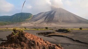 A volcanic landscape with a prominent mountain in the background. - Red lava show lodge (Tanna Island)