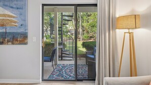Une pièce dotée d’une porte-fenêtre coulissante donnant sur un balcon aménagé avec du mobilier d’extérieur et un escalier en colimaçon.
