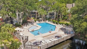 Un espace piscine comprenant des chaises longues, une terrasse en bois et un bassin d’eau.