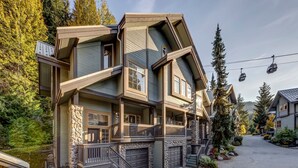 A multi-story house with a stone facade, large windows, and a front porch. - Snowy Creek 14 - True Ski in Ski out, easy walk to Whistler Village, Private Garage. (Whistler)