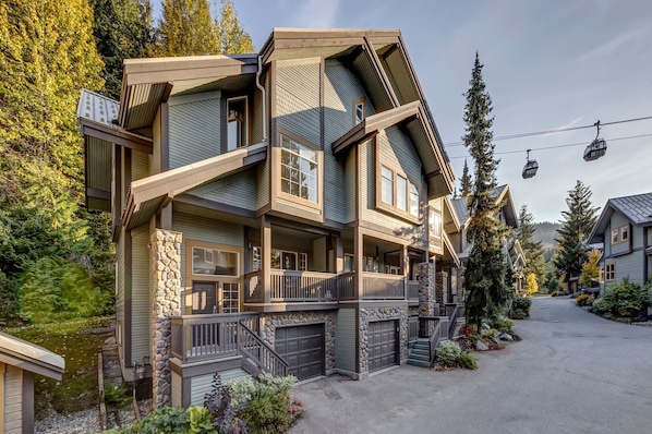 A multi-story lodge with a stone facade, balconies, and a ski lift in the background.