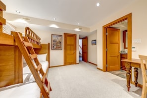 A room with a bunk bed, wooden doors, a framed picture on the wall, and a small table.