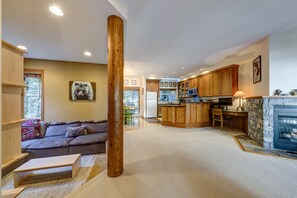 Ein großzügiger Wohnbereich mit einer Couch, einer Holzsäule, einer Küche mit Holzschränken und einem Kamin.