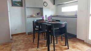 Een compacte keuken met een eettafel voor vier personen, compleet met zwarte stoelen en paars servies.