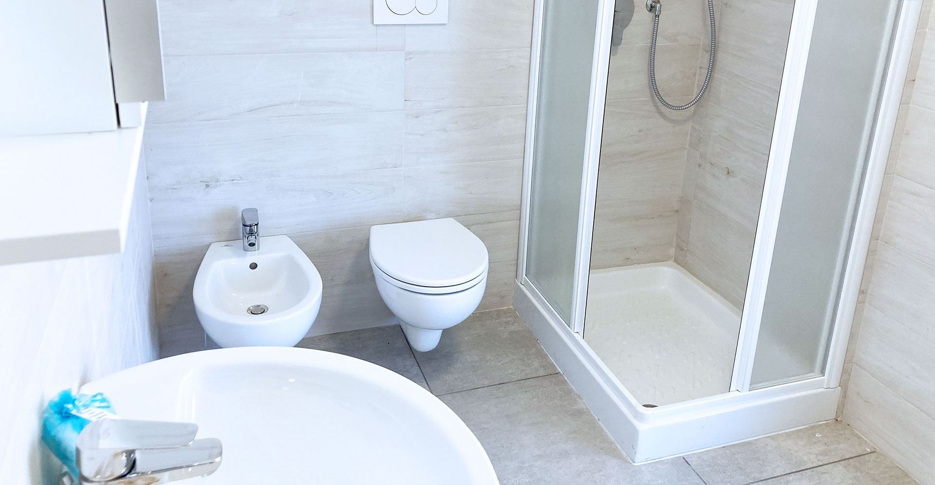 Un bagno con lavabo su piedistallo, bidet, wc e box doccia in vetro.
