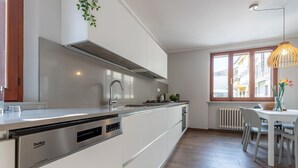 Eine moderne Küche mit integriertem Geschirrspüler, einer Edelstahl-Dunstabzugshaube und einem Fenster mit Blick auf eine Wohngegend.