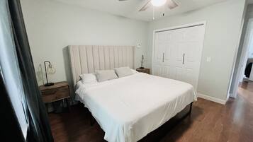 A bedroom with a bed, a ceiling fan, a nightstand, a lamp, and a wardrobe.