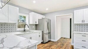 A modern kitchen with white cabinetry, a stainless steel refrigerator, and a marble countertop. - Top 5% • 3BR Gem • Prime Location, Special Backyard, Great Hosts  (Huntsville)
